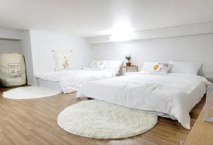 een slaapkamer met 2 bedden met witte lakens en tapijten bij Loco House in Incheon