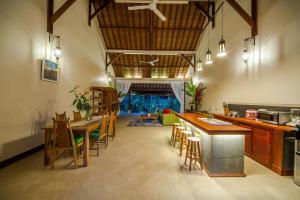 a large kitchen with wooden tables and chairs at Luxury 3BR Infinity Jungle View Aashaya Villa Ubud in Ubud