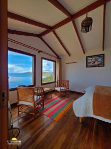 a bedroom with a bed and two chairs and windows at Utasawa in Comunidad Yumani