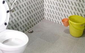 a bathroom with a white toilet and a yellow trash can at Koilee Homestead by StayApart in Darjeeling