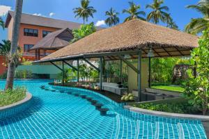 a swimming pool at a resort with a thatch roof at Courtyard by Marriott Phuket, Patong Beach Resort in Patong Beach