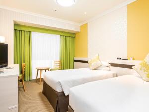 a hotel room with two beds and a television at Oriental Hotel Tokyo Bay in Urayasu