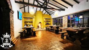 a restaurant with wooden tables and a fireplace at La Villa de San Sebastian Hotel in Villa de Leyva