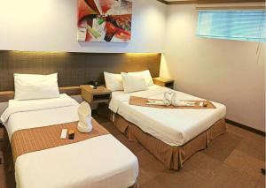 a hotel room with two beds with white sheets at Magallanes Square Hotel Inc. in Tagaytay