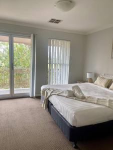 Un dormitorio con una cama grande y un balcón. en Serene Wagga Townhouse Getaway, en Wagga Wagga