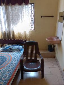 a bedroom with a chair and a bed and a sink at St. Antonys Lodge in Cochin