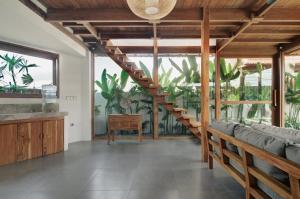 a living room with wooden stairs and plants at Villa Sunshine in Munggu