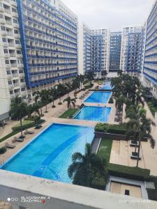 an overhead view of three pools in a city with tall buildings at ARISE shell Residences in Manila