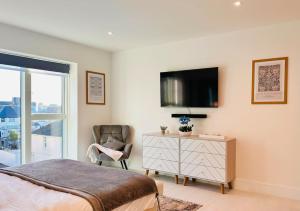 a bedroom with a bed and a chair and a tv at 34 Cliff Edge 2nd floor Newquay luxury sea-view residence in Newquay