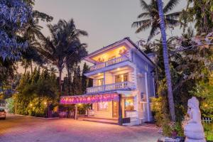 a blue house with a balcony and palm trees at Joia Do Mar Resort - Calangute in Calangute