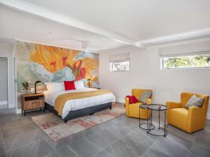 a bedroom with a bed and two yellow chairs at Bluemari's Retreat in Hout Bay