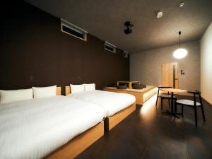 a bedroom with two beds and a table and a desk at Rakuten STAY Hakata Gion 402 Deluxe Room in Fukuoka