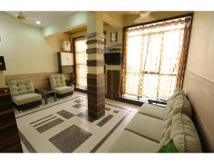 a living room with a couch and chairs and windows at Hotel Ronak Royal, Porbandar in Porbandar