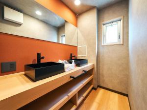 Rakuten STAY Hakata Gion 502 Deluxe Room في فوكوكا: حمام مع حوض أسود وجدار برتقالي