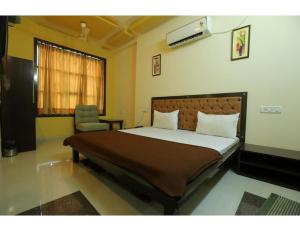 sypialnia z dużym łóżkiem i krzesłem w obiekcie Hotel Ronak Royal, Porbandar w mieście Porbandar