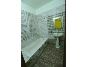 ein Badezimmer mit einer Badewanne und einem Waschbecken in der Unterkunft Hotel Ronak Royal, Porbandar in Porbandar