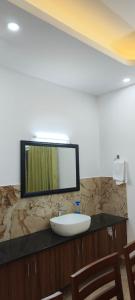 ein Badezimmer mit einem Waschbecken und einem Spiegel auf der Theke in der Unterkunft Woodland Escape Villas by Lexstays in Ettumānūr
