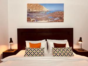 ONE Prestine Beach Villa في مسقط: غرفة نوم بسرير ومخدات ولوحة