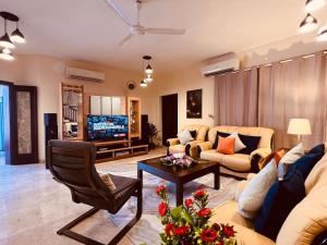 a living room with a couch and a tv at ONE Prestine Beach Villa in Muscat