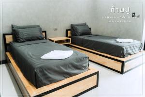 two beds in a room with wooden bases at Khampu Resident ก้ามปู เรสซิเด้นท์ in Maha Sarakham
