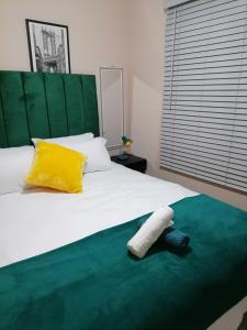 a bedroom with a white bed with a yellow and green headboard at Peaceful Home with Sbo in Pietermaritzburg