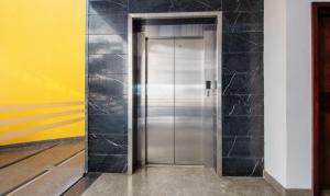 a silver elevator in a room with a yellow wall at Treebo Brahma, Wayanad in Sultan Bathery +23 photos
