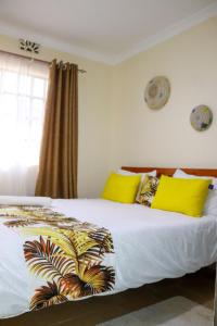 a bedroom with a large bed with yellow pillows at Fully Furnished 2BR Eclectic Homestay near UOE in Eldoret