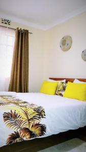 a bedroom with a bed with yellow pillows at Fully Furnished 2BR Eclectic Homestay near UOE in Eldoret