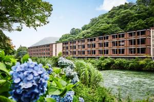 un edificio di fronte a un fiume con fiori di Hotel Indigo Hakone Gora, an IHG Hotel a Hakone