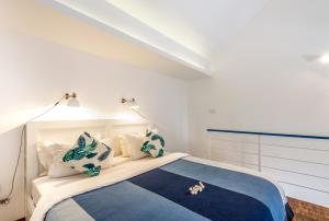 The Blue Loft Seminyak free scooter في سمينياك: غرفة نوم مع سرير ووسائد زرقاء وبيضاء