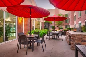 een patio met tafels en stoelen met rode parasols bij Residence Inn Salt Lake City Sandy in Sandy