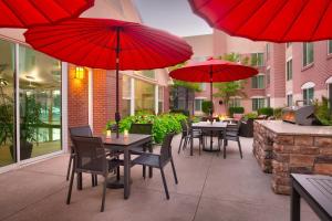 un patio con mesas y sillas y sombrillas rojas en Residence Inn Salt Lake City Sandy, en Sandy