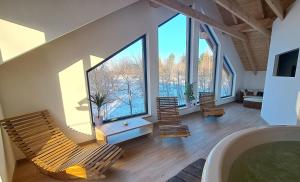 a room with chairs and a tub with large windows at wellness roubenka Holčí in Miřetice