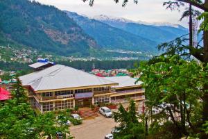 un edificio con auto parcheggiate di fronte a una montagna di Hotel Ishaan a Manāli