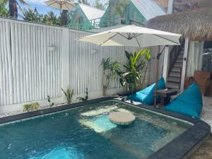 a swimming pool with an umbrella and a table and chairs at Rascal House Gili Trawangan in Gili Trawangan