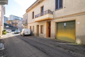 um edifício com uma porta de garagem verde numa rua em Nausica's Apartment em Trinità d'Agultu e Vignola