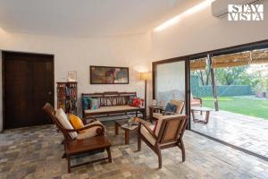 a living room with chairs and a couch at The Courtyard by StayVista - Private Pool with Rustic Charm, Vibrant Courtyard, Spacious Verandah & Garden in Alibag