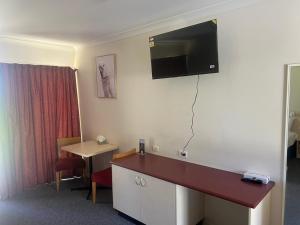 Habitación de hotel con TV de pantalla plana en la pared en Outback Quarters Motel Hay and Restaurant, en Hay
