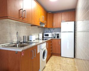 a kitchen with wooden cabinets and a white refrigerator at Casa Lilla - Ideal for couples in Los Alcázares
