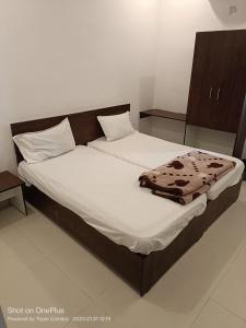 a bed with white sheets and a blanket on it at Durga Pride in Kurnool