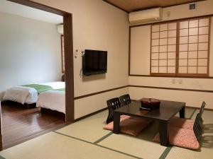 屋久島にある天然温泉と縄文の宿「まんてん」のベッド、テーブル、テレビが備わる客室です。