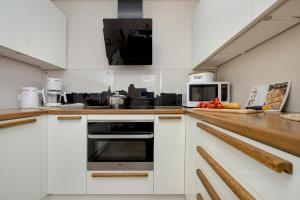 a kitchen with white cabinets and a stove top oven at Blue Apartment Słowackiego with Balcony and Parking in Gdańsk by Renters in Gdańsk