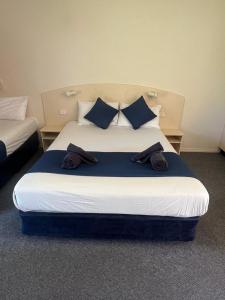 ein Schlafzimmer mit einem großen Bett mit blauen Kissen in der Unterkunft Outback Quarters Motel Hay and Restaurant in Hay