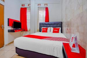 a bedroom with a bed with red pillows and a tv at OYO Life 90035 Merci Club in Bandung