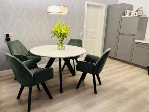 uma mesa de jantar com cadeiras e um vaso de flores em Hof Steinhütten Boutique Apartments em Westerhever