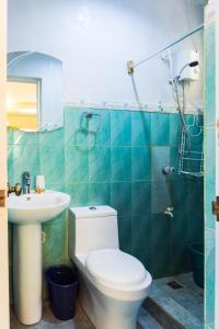 a bathroom with a toilet and a sink and a shower at High Chaparral Cottages in El Nido
