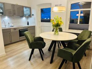 eine Küche mit einem Tisch mit Stühlen und einer Vase aus Blumen in der Unterkunft Hof Steinhütten Boutique Apartments in Westerhever