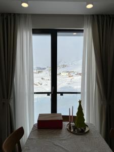 a table with a christmas tree in front of a window at Cozy one bedroom apartment in New Gudauri in Gudauri