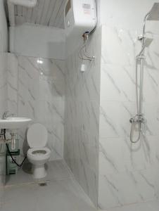 uma casa de banho branca com um chuveiro e um WC. em SECOND HOPE LODGE em Padang