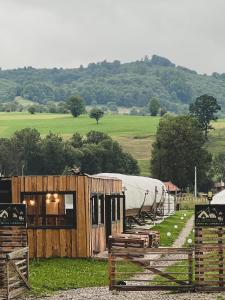 a wooden building with a tent in a field at Glamping Iurte Mongole Spiritul Zimbrului in Vama Buzăului